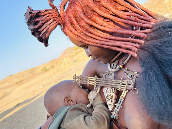 himba woman breastfeeding her child Visiting a himba village from Hoanib Valley Camp Kaokoland with Natural Selection Travel Danica Wilson 2023