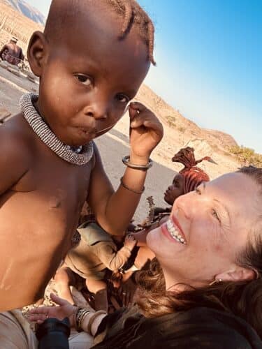 Danica with himba child Visiting a himba village from Hoanib Valley Camp Kaokoland with Natural Selection Travel Danica Wilson 2023